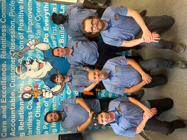 First Care's technicians kneeling in front of a poster of their values.